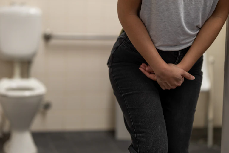 Person holds their groin in a public toilet