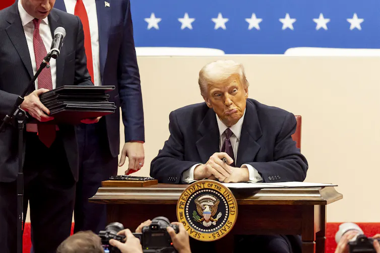 Donald Trump signs a series of executive actions on stage during a presidential inaugural event at the Capitol One Arena in Washington, DC, USA, 20 January 2025.