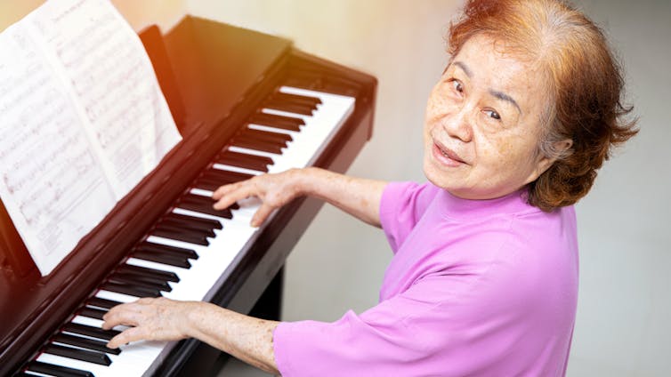 An older woman learning to play the piano.