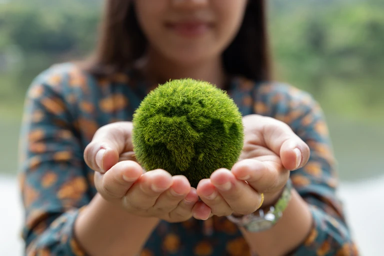 Une jeune femme tient une planète verte dans ses mains
