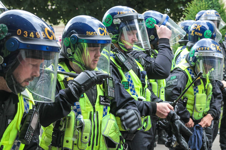 A line of police in helmets with face shields