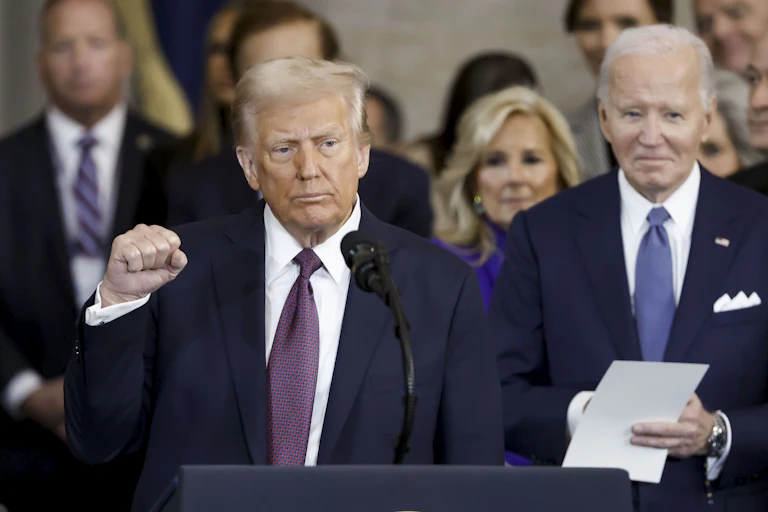 Donald Trump clenches his fist as he stands in front of former [resident Joe Biden after being inaugurated as 47th US president.