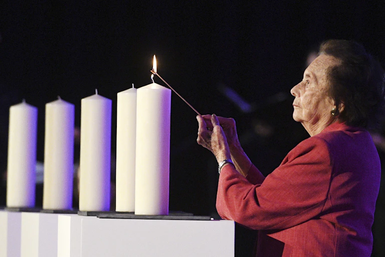 Lily Ebert lighting a large white candle.