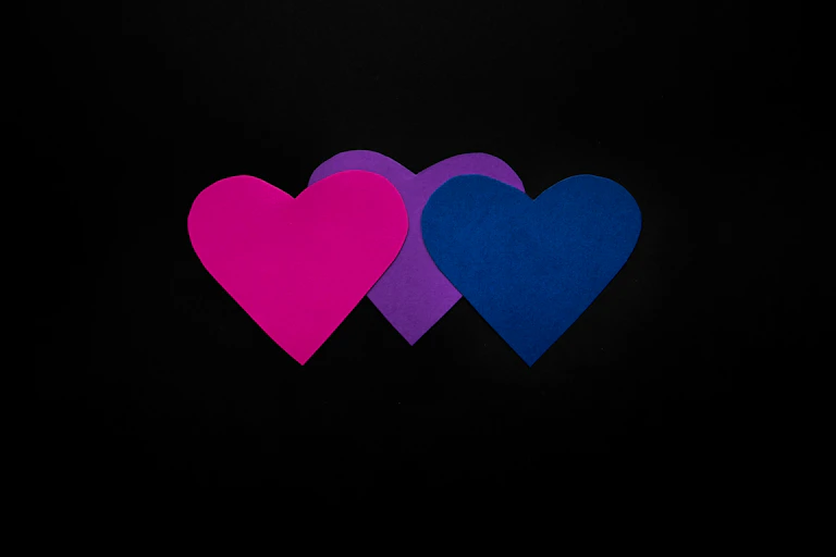 three pink purple hearts on black background