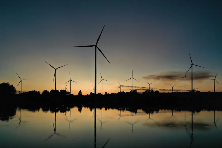 wind turbines reflected in water at dusk