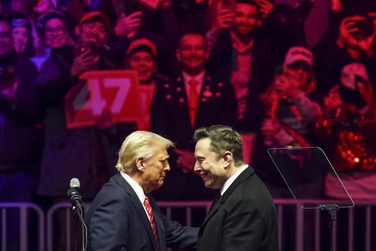 The profiles of two men facing each other in front of a large crowd