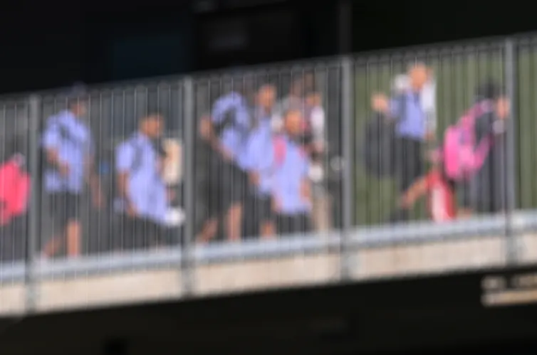 A blurred image of young students walking across a bridge.