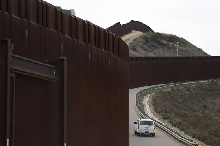 A border patrol vehicle drives along the US-Mexico border.