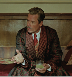 The Brutalist: an architect’s tackle a movie about one guy’s adventure to grasp his visionary construction 1 A seated man dressed in a smoking jacket drinking a cocktail.