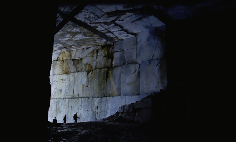 The Brutalist: an architect’s tackle a movie about one guy’s adventure to grasp his visionary construction 2 Three humans looking tiny inside the huge Carrara marble quarry in Italy.