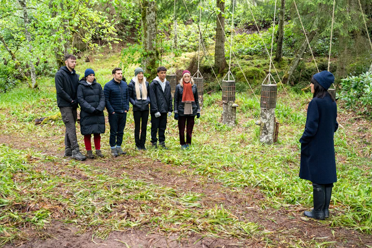 The Traitors team standing in the woods.