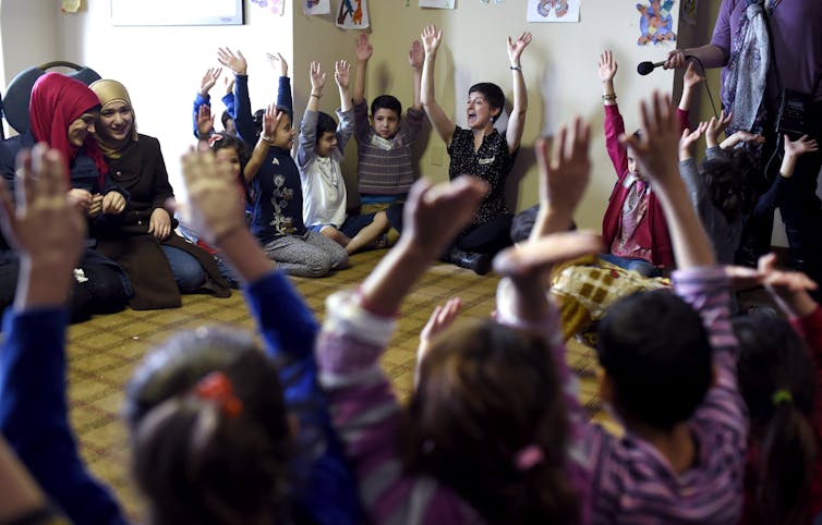 Adults and children seated in a circle.