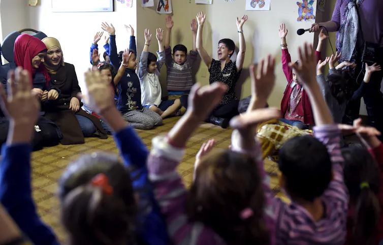 Adults and children seated in a circle.