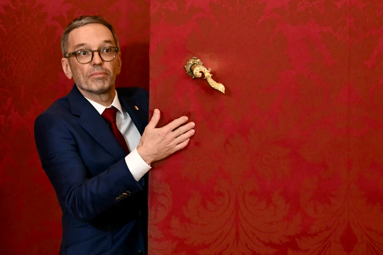Un homme se tient derrière une porte rouge.