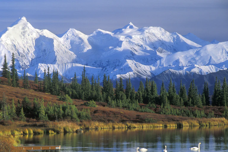 Scenic landscape of snow-covered mountains and a lake with swans