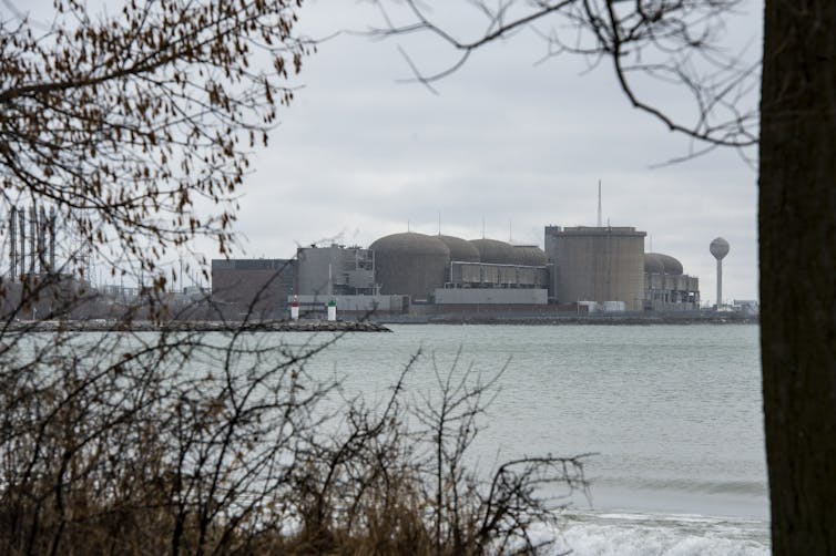 A series of large grey concrete structures on the shore of a lake