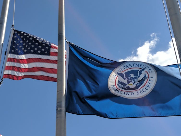 an american flag and a fema flag — blue with centred white government symbol — fly at half mast