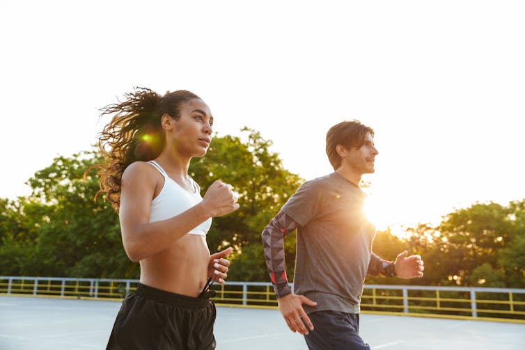 A young fit man and woman go for a run outdoors.