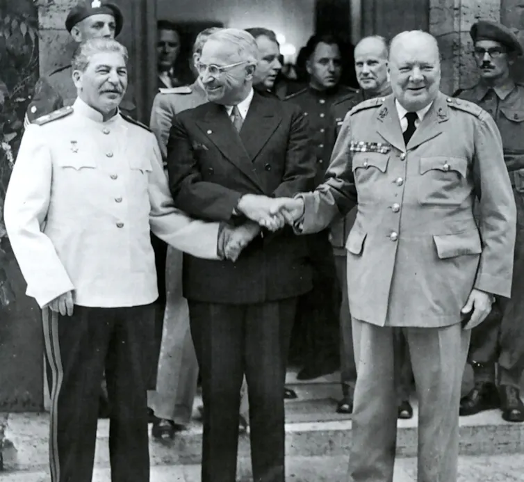 Harry Truman shaking hands with Joseph Stalin and Winston Churchill.