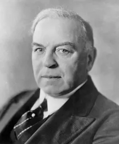 A black-and-white photo of a man with thin white hair.
