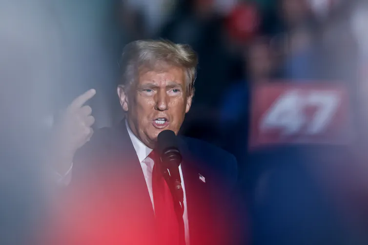 Donald Trump at a podium with his hand raised.