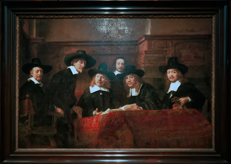 An oil painting showing sic European men at a table covered in a rich red cloth with a book on it. They are dressed in black and white finery with large collars and hats.