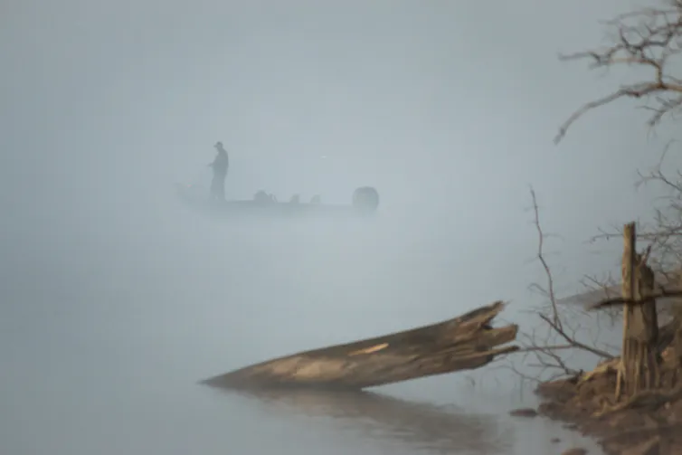 A fishing boat leaving a harbour at dusk.
