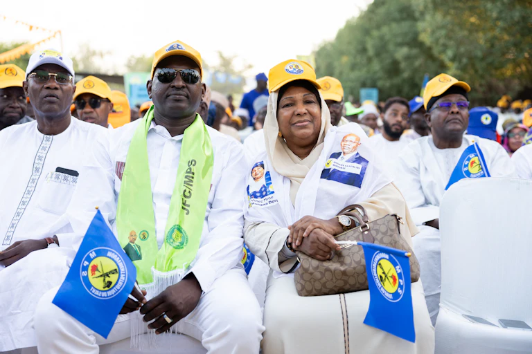 Men and women wearing white traditional attires with yellow caps