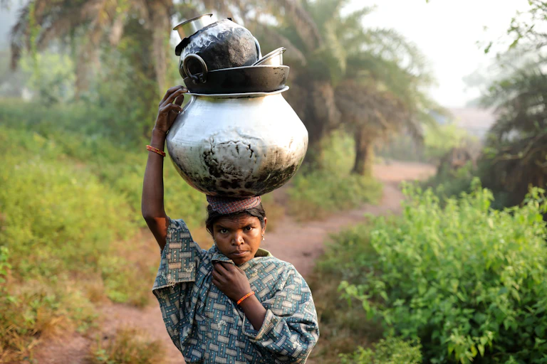 A woman from an Indian tribal community walks through a forest.