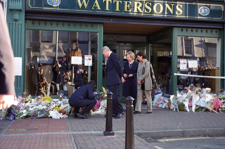 Bill and Hillary Clinton with Cheri and Tony Blair looking at memorial flowers laid outside a shop called Waterson's.