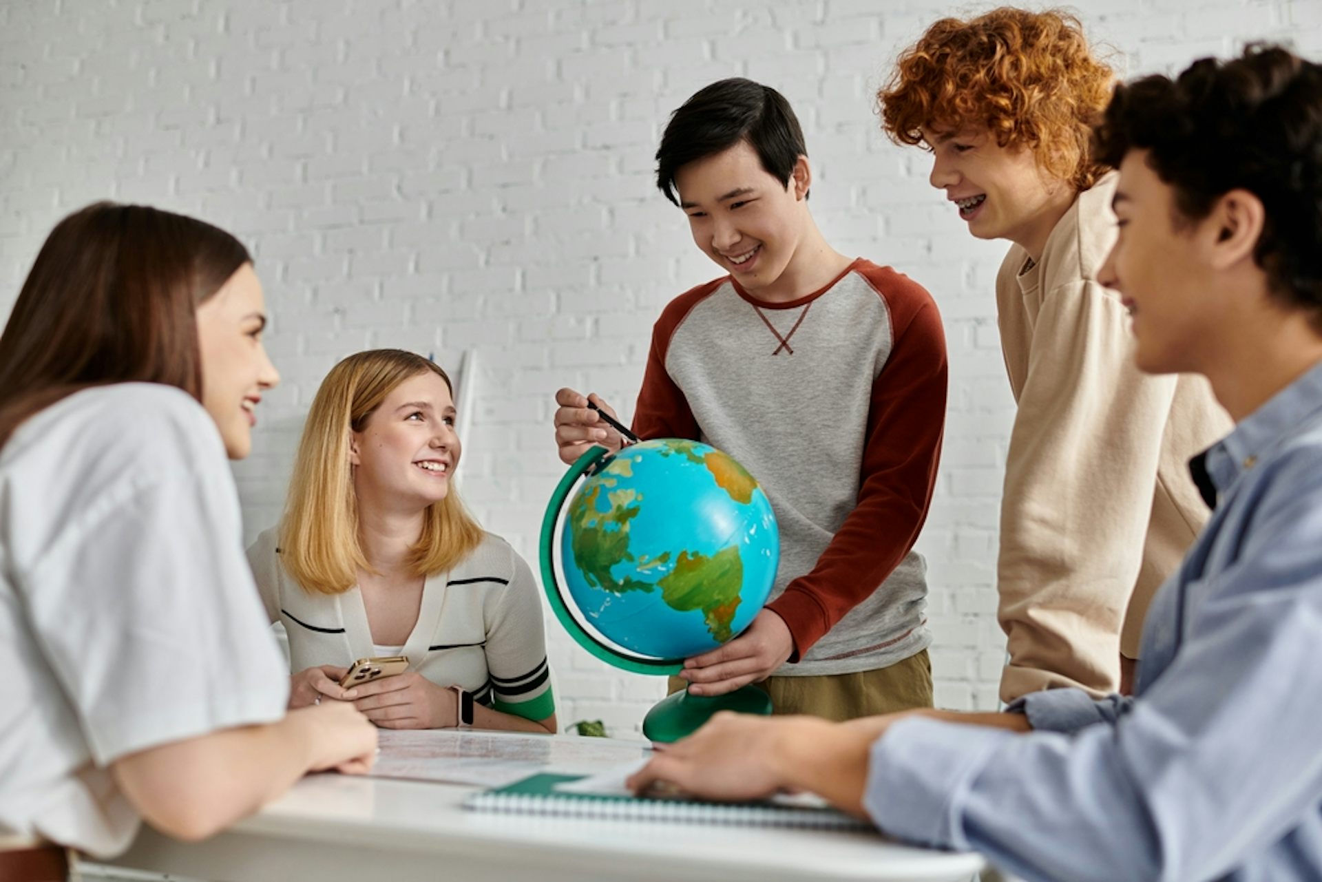 Des adolescents discutent autour d’un globe