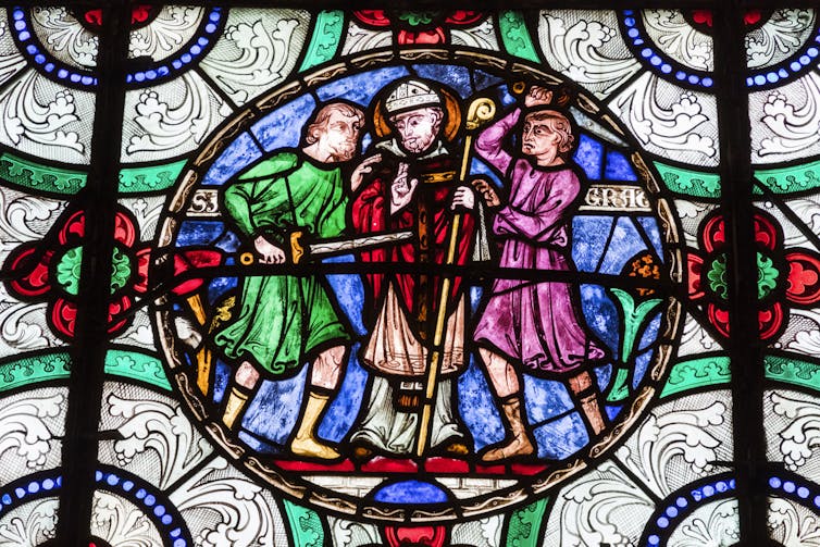 A painting depicts three men: one inserting a sword into the man in the middle, while the third, standing to the side, appears to strike with his sword.