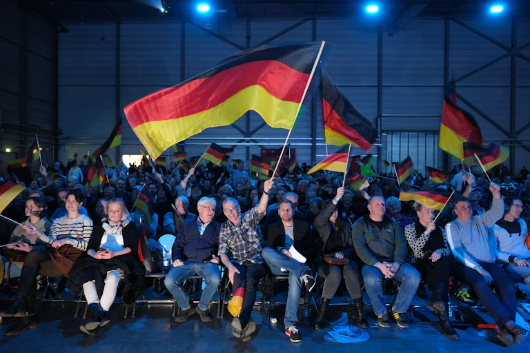Men and women sitting in rows waving German flags