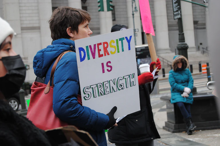 woman protester holding a sign that reads 'diversity is strength'