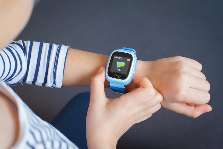 A child looks at a smart watch on their wrist.