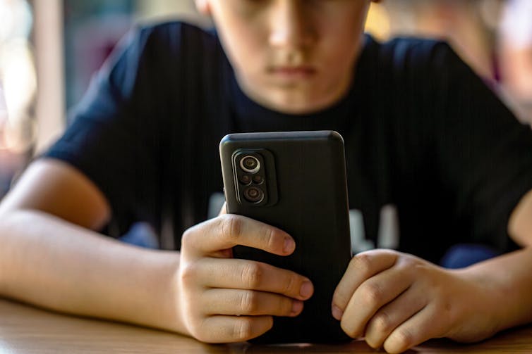 A young boy looks at a phone.