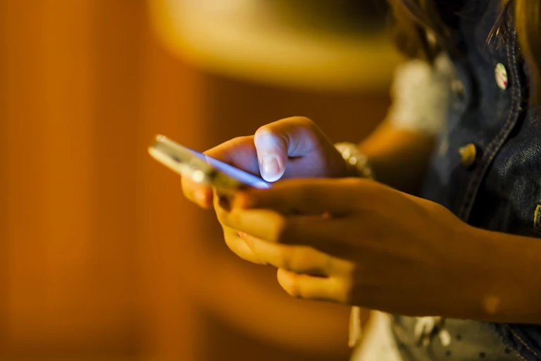 A young person holds a phone.
