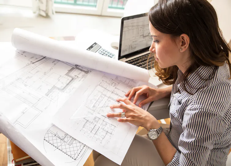 A young woman looking over blueprint drawings of a building
