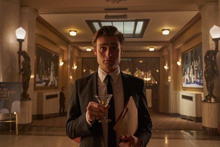 Young man in a suit holding a martini.