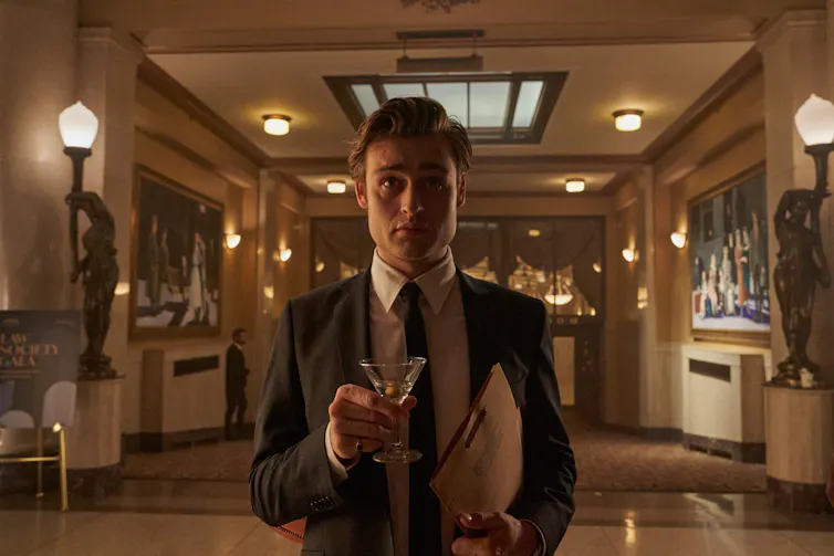 Young man in a suit holding a martini.