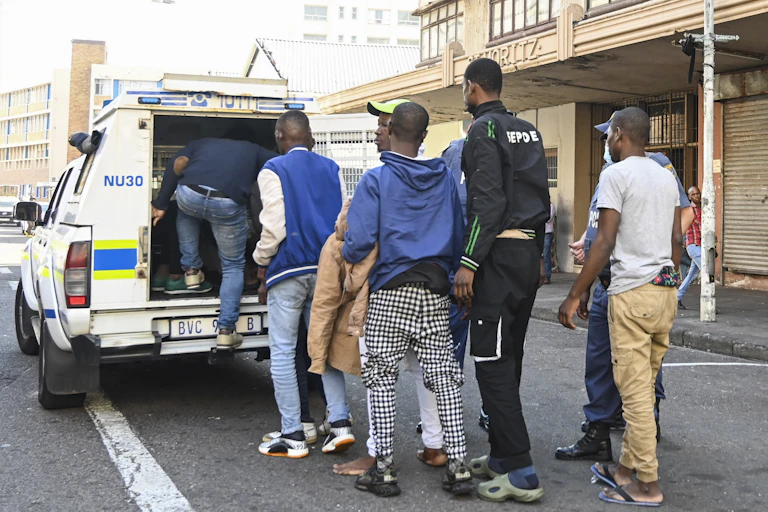 Men line up to get into the back of a police van
