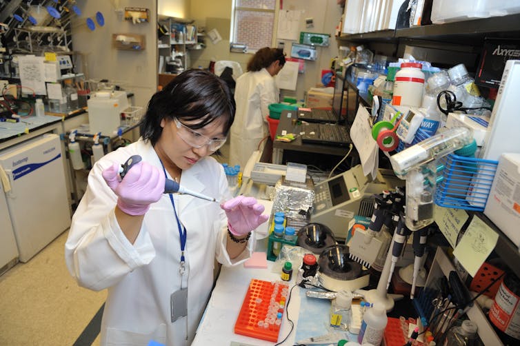A woman in a lab coat doing an experiment in a medical lab.
