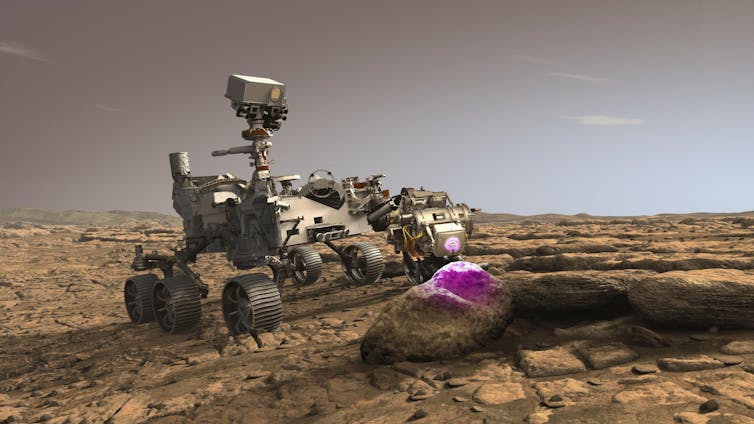 a mars rover shines a purple light onto a rock
