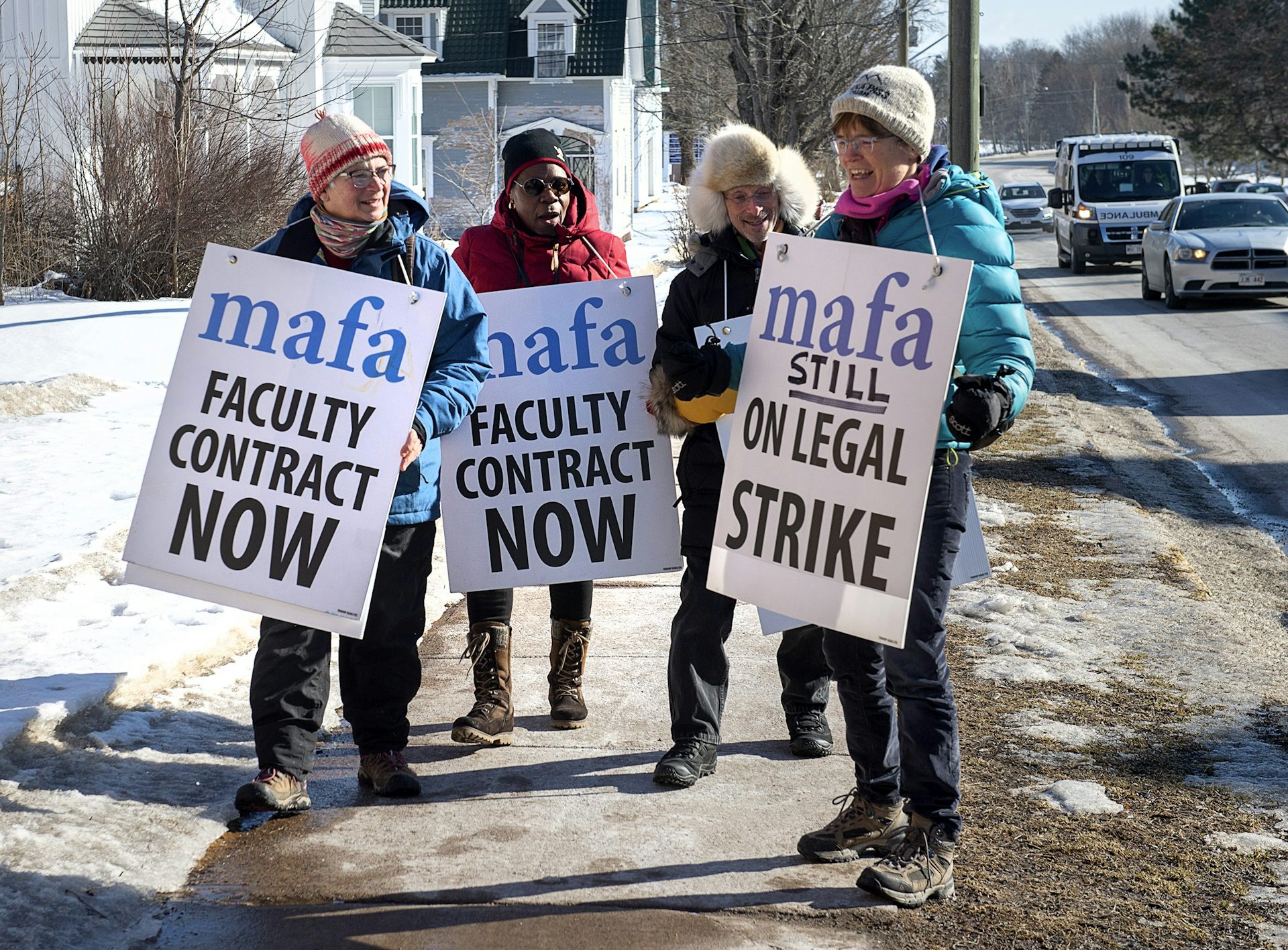 Strikers with signs that say 'faculty contract now.'
