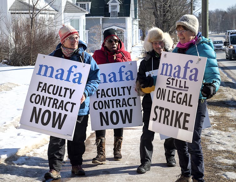 Strikers with signs that say 'faculty contract now.'