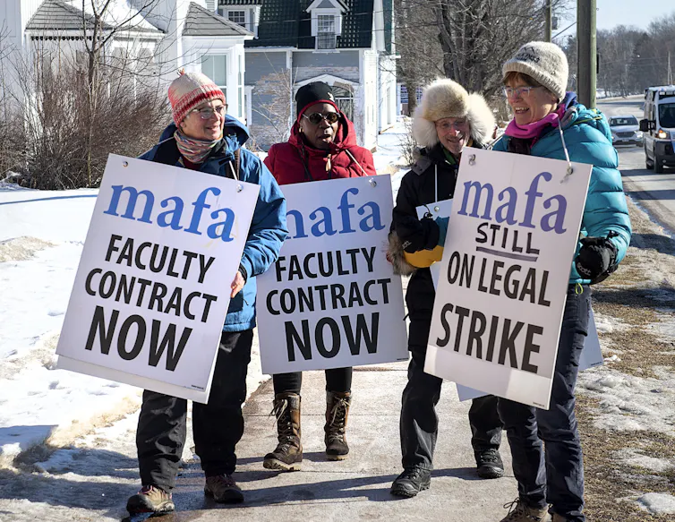 Strikers with signs that say 'faculty contract now.'