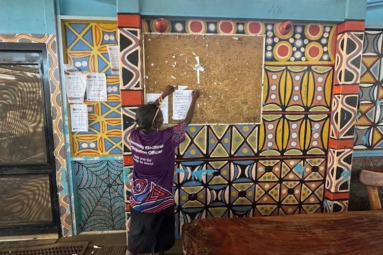A woman putting up a poster.