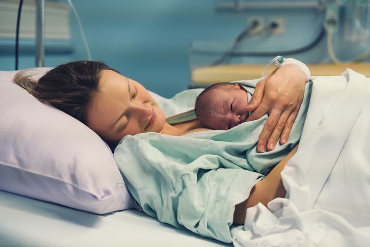 A woman in hospital holding a newborn baby.