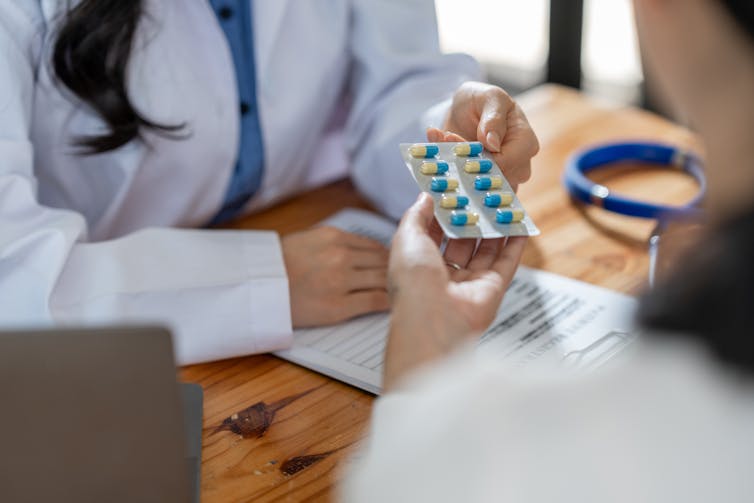 A doctor hands a patient a blister pack of pills.