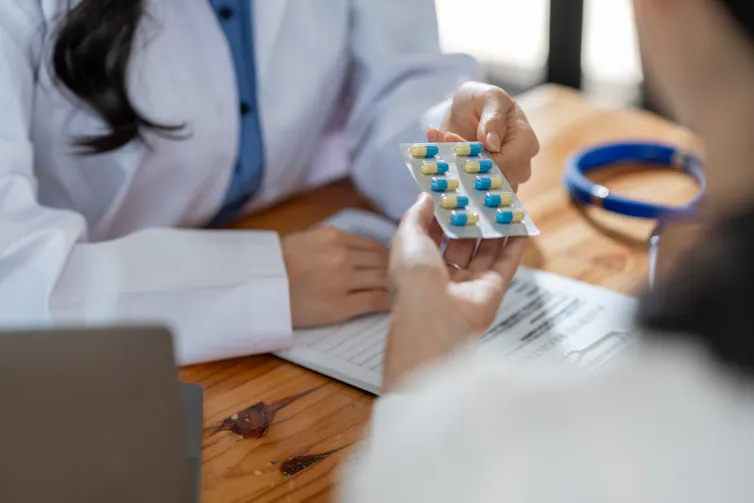 A doctor hands a patient a blister pack of pills.
